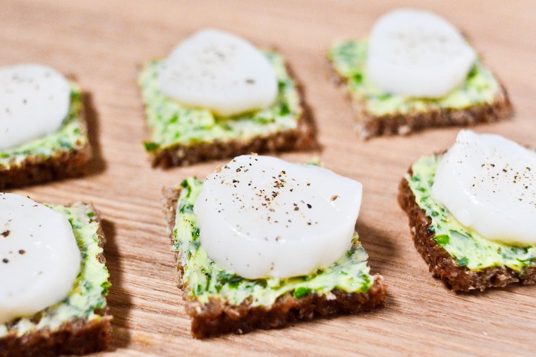 A chic yet easy nibble. Learn how to make herbed butter! Spread it on pumpernickel bread with a sliced scallop on top. Great for a special occasion buffet!